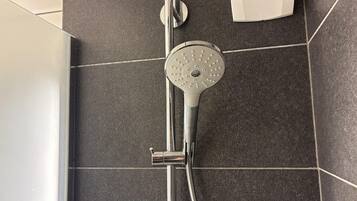 Een douche met een handdouche, een kraan van chroom en een betegelde vloer.