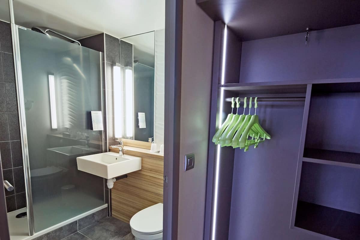 Un baño moderno con cabina de ducha de vidrio, un lavamanos blanco y un inodoro.