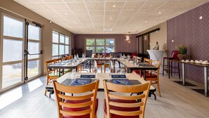 Un comedor amplio con varias mesas y sillas, ventanas grandes y un diseño moderno de techo.