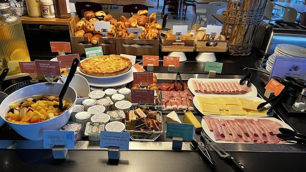 Un bufé con diversas opciones de comida, incluyendo frutas, quesos, carnes y pasteles.