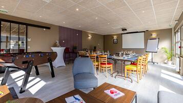 A modern conference room with a pool table, comfortable seating, and a projector screen.