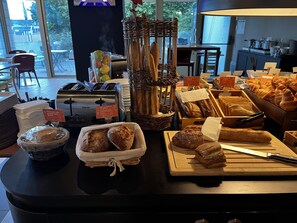 A bakery counter with bread, baguettes, and a toaster. - Campanile Dijon Nord - Toison d'Or (Dijon)