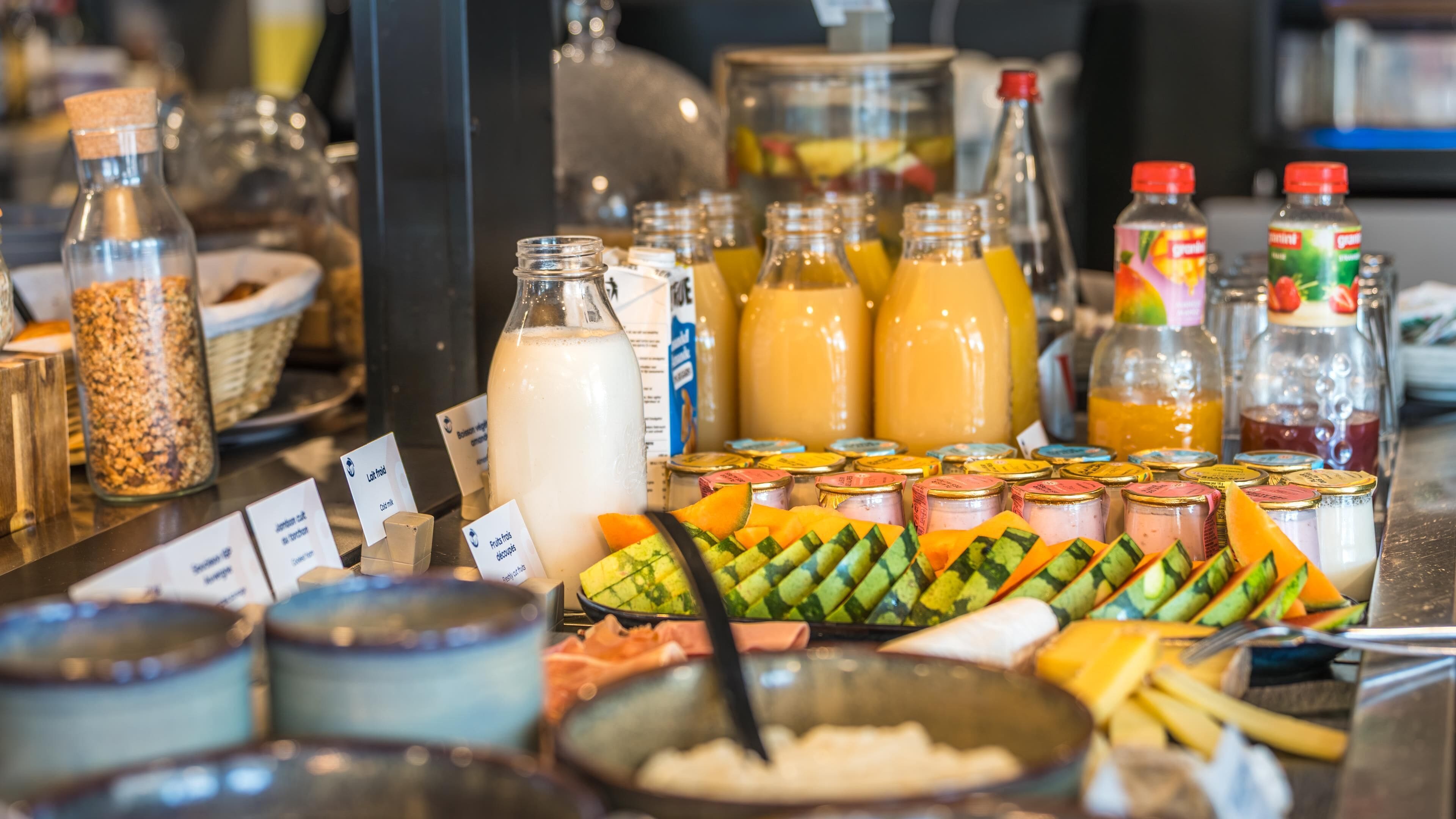 A buffet with various food items and beverages, including fruits, cheeses, and milkshakes.