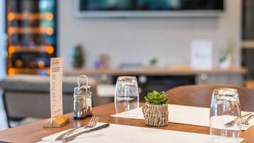 A table set with a menu, salt and pepper shakers, a small succulent plant, and a glass of water.