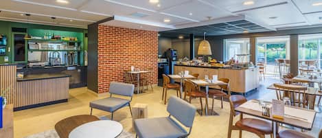 Een modern café met een geaccentueerde bakstenen muur, houten tafels en stoelen, een bar en uitzicht op het buitenlands landschap.