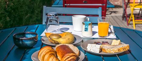 A table with breakfast items including croissants, bread, fruit, and a glass of orange juice.