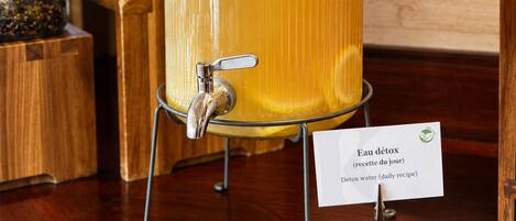 A glass jar with a tap, labeled 'Eau détox,' on a wooden table.