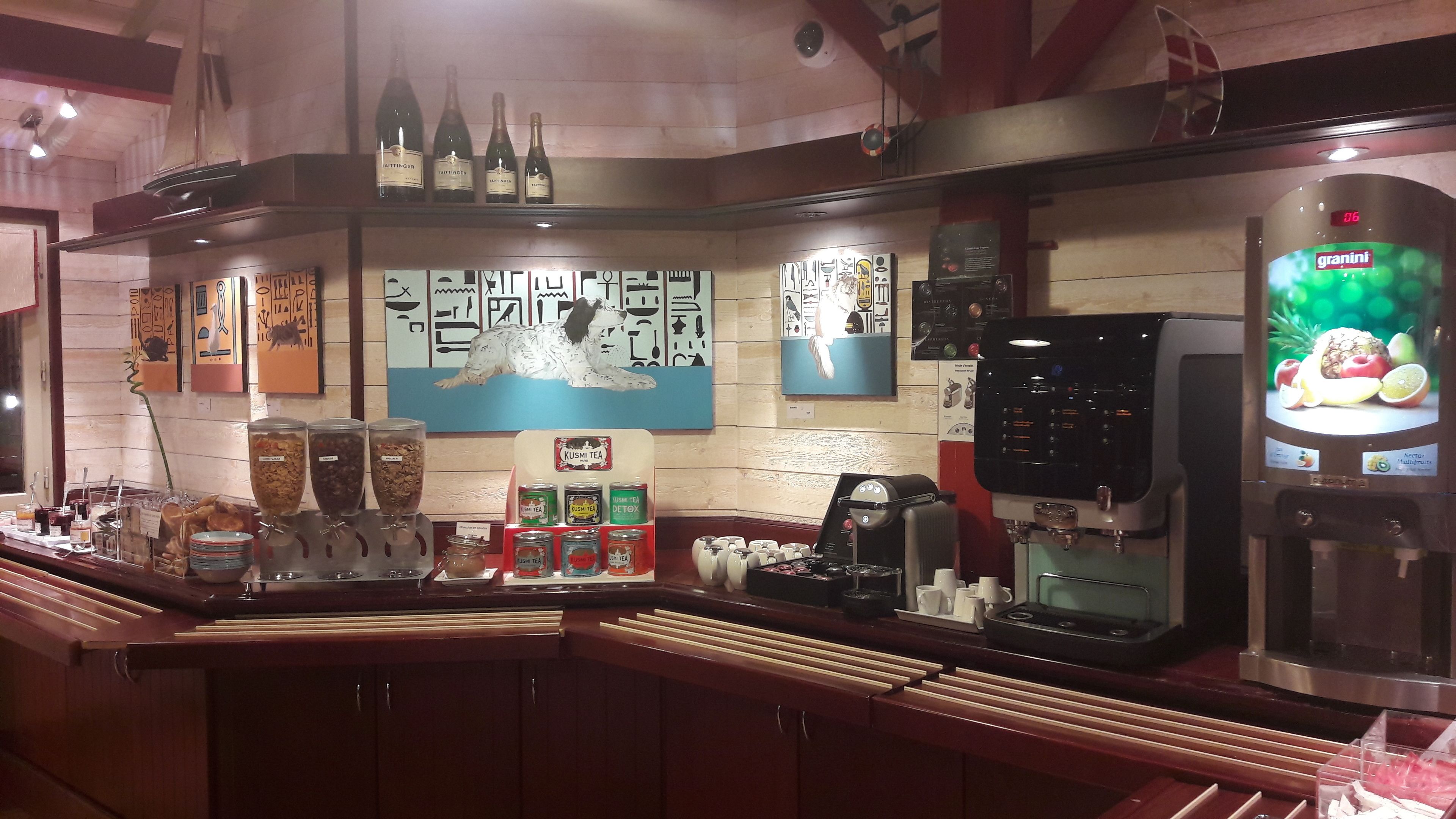 Zona de bar con mostrador, diversas bebidas y una pantalla digital con el menú.