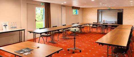 A conference room with tables, chairs, a projector, and a whiteboard.