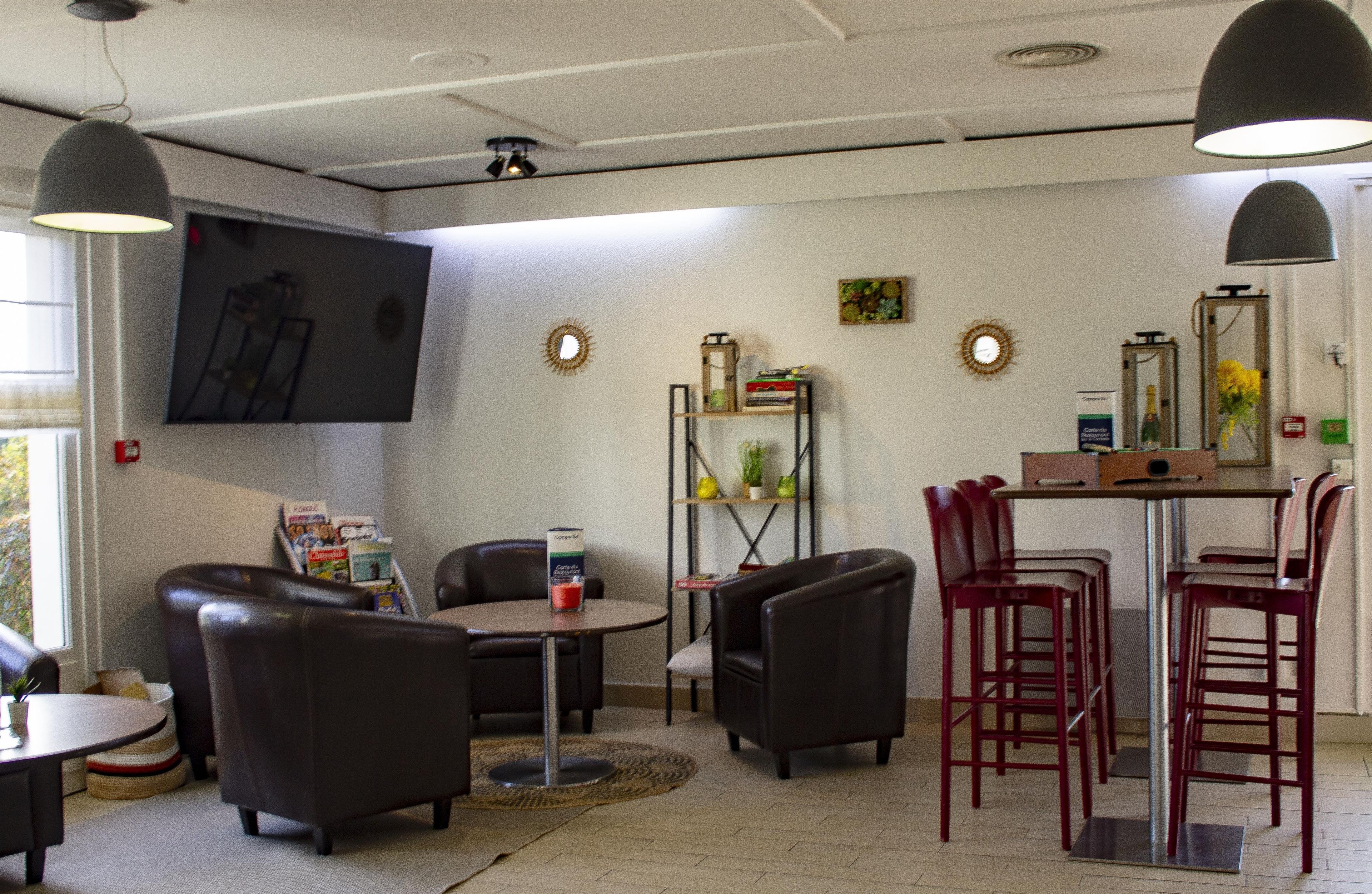 A room with a round table, two chairs, a bookshelf, and a bar area with stools.
