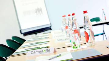 A conference room with tables, chairs, water bottles, name cards, and a presentation screen.