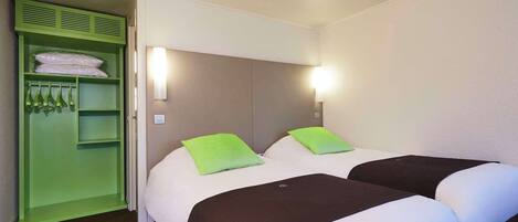 Habitación de hotel con dos camas, un armario verde y una lámpara fijada a la pared.