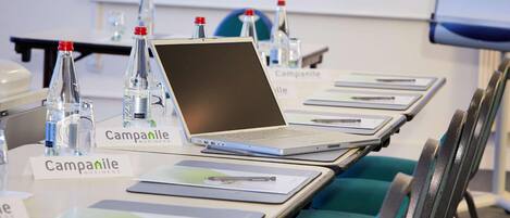 Una mesa de conferencias con computadoras portátiles, placas de identificación y botellas de agua.