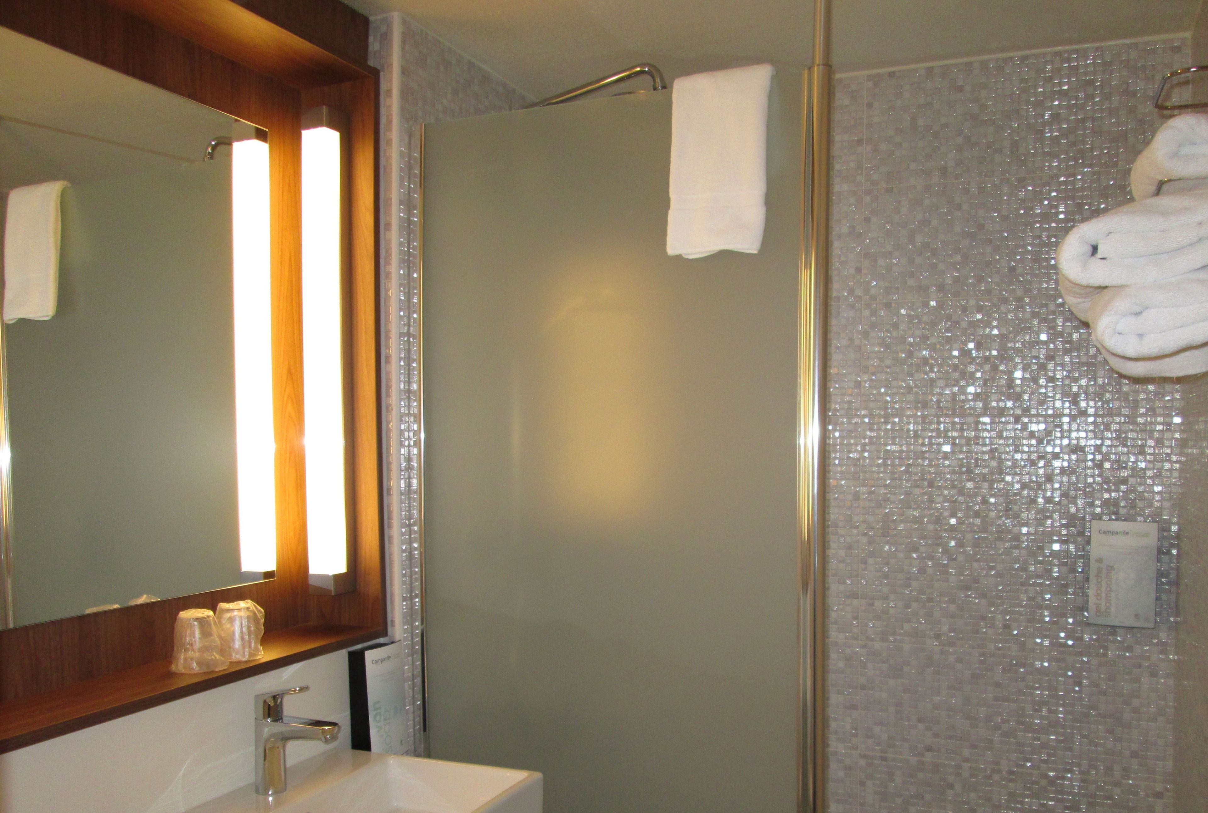 A bathroom with a shower, a sink, and a mirror.