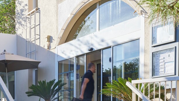 A building entrance with a glass door, a staircase, and potted plants. - Hôtel Cyano Fréjus-Saint Raphaël (Fréjus)