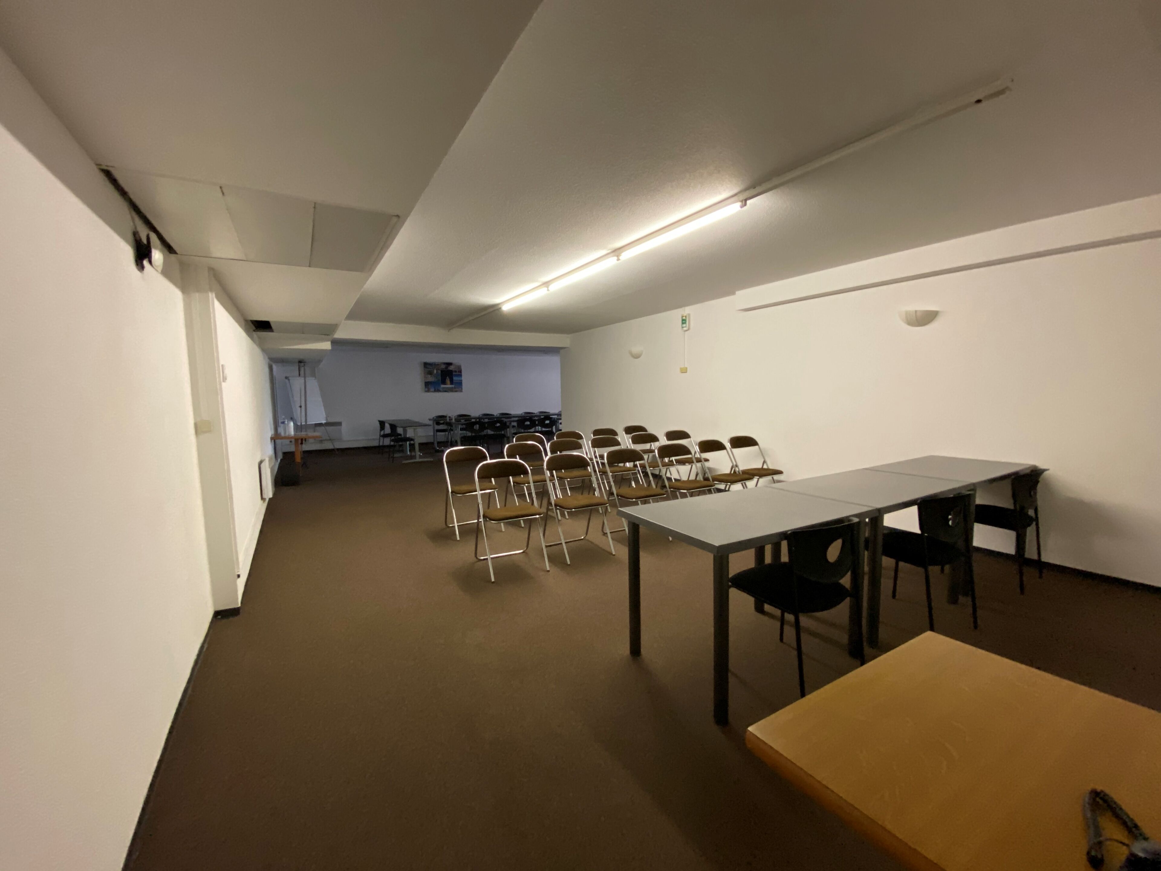 A conference room with a long table, several chairs, and a smaller table.