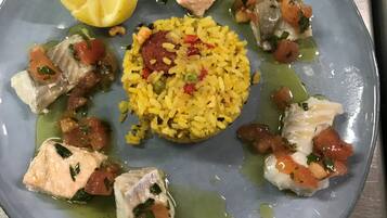 A plate of food with rice, fish, and lemon.