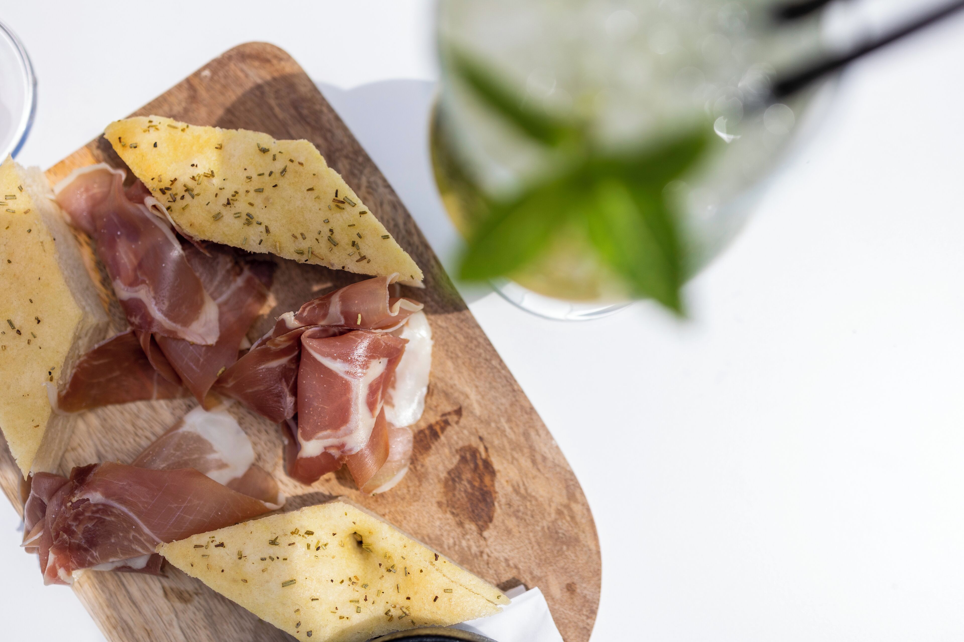 A wooden board with sliced cured meats and cheese.