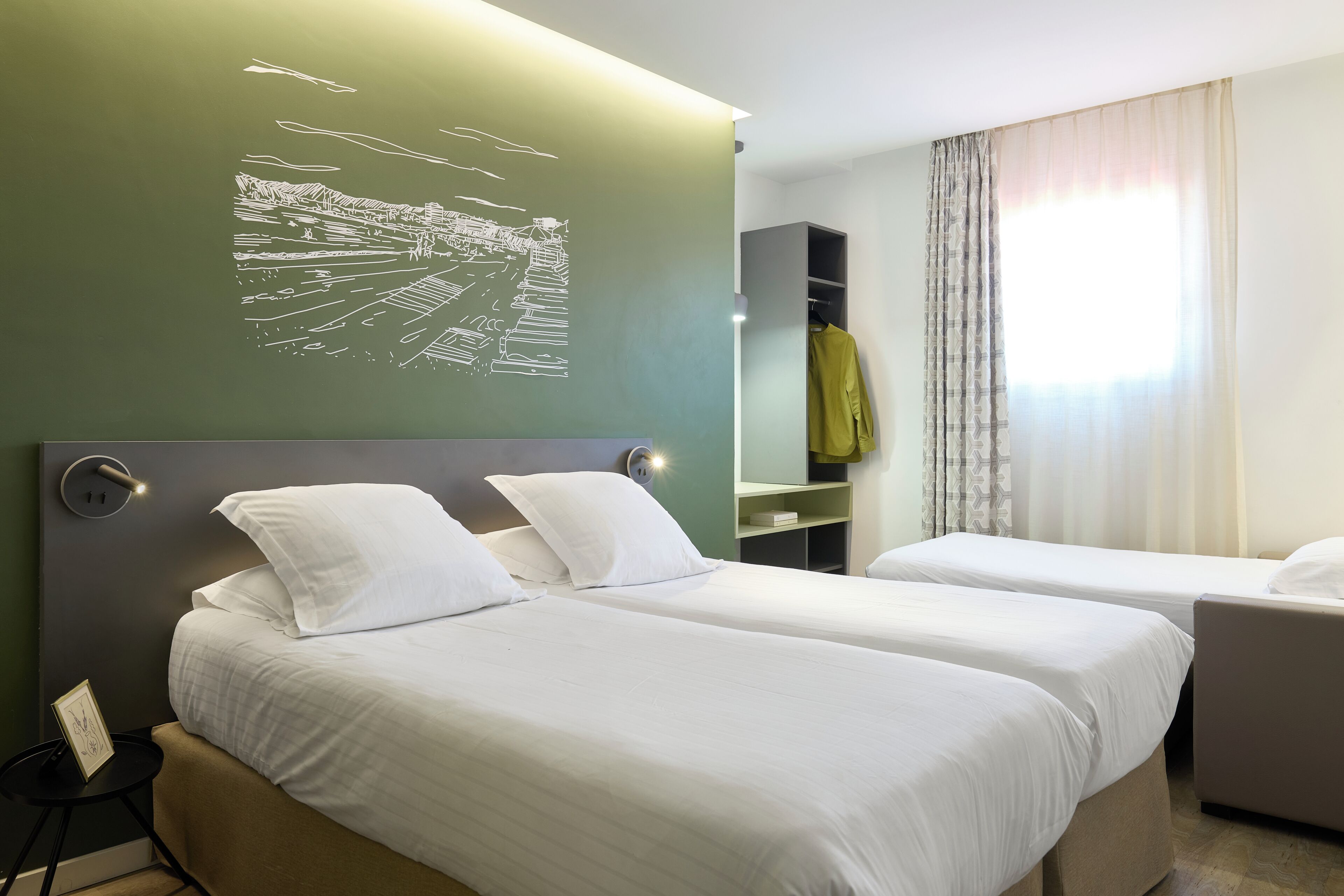 Habitación de hotel con dos camas, un escritorio, una silla, un armario y una obra de arte colgada en la pared.