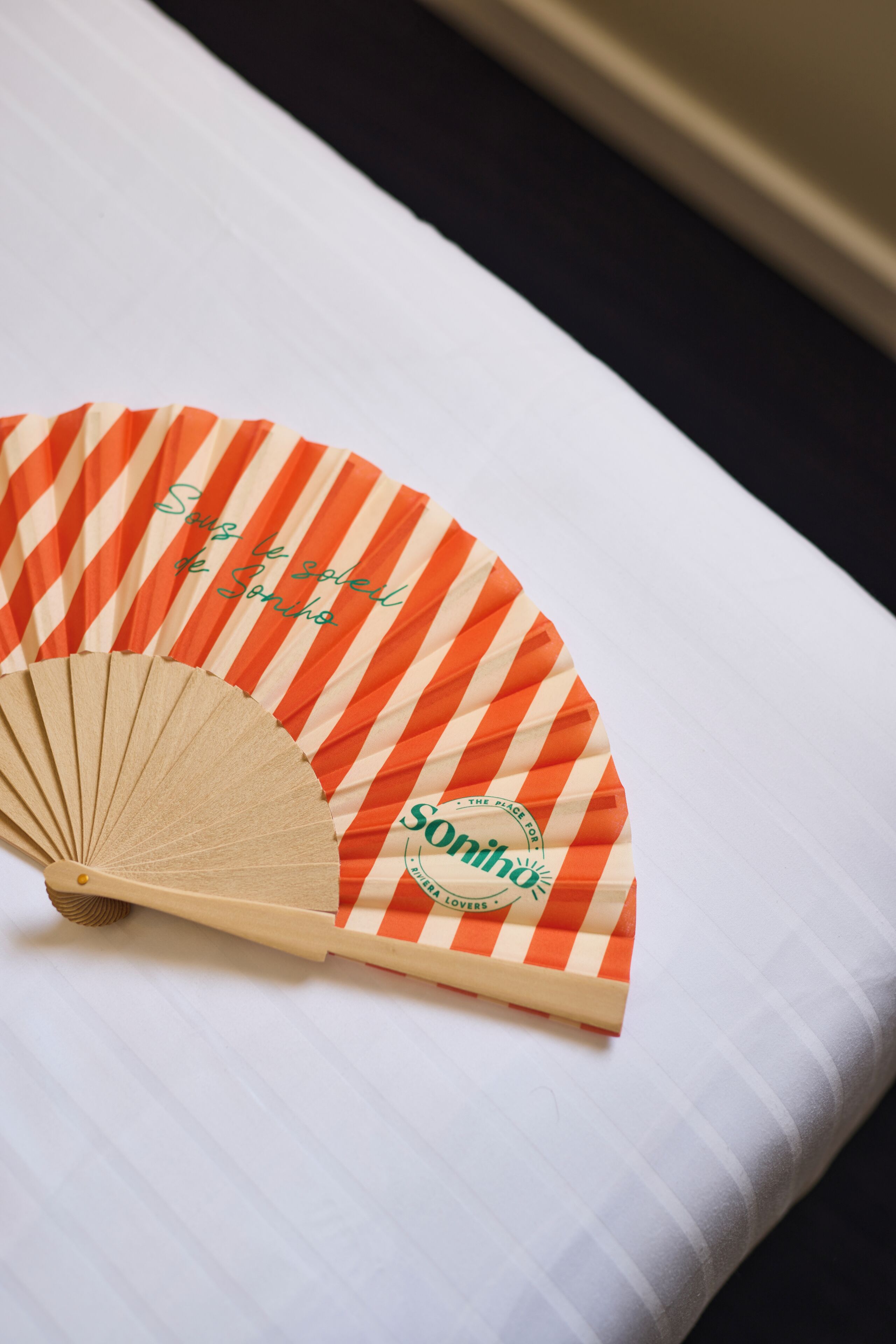 A fan with orange and white stripes and the text 'Sonsinho' on a white pillow.
