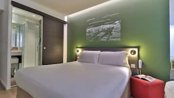 Un dormitorio moderno con una cama grande, un pouf rojo y una lámpara de pared.
