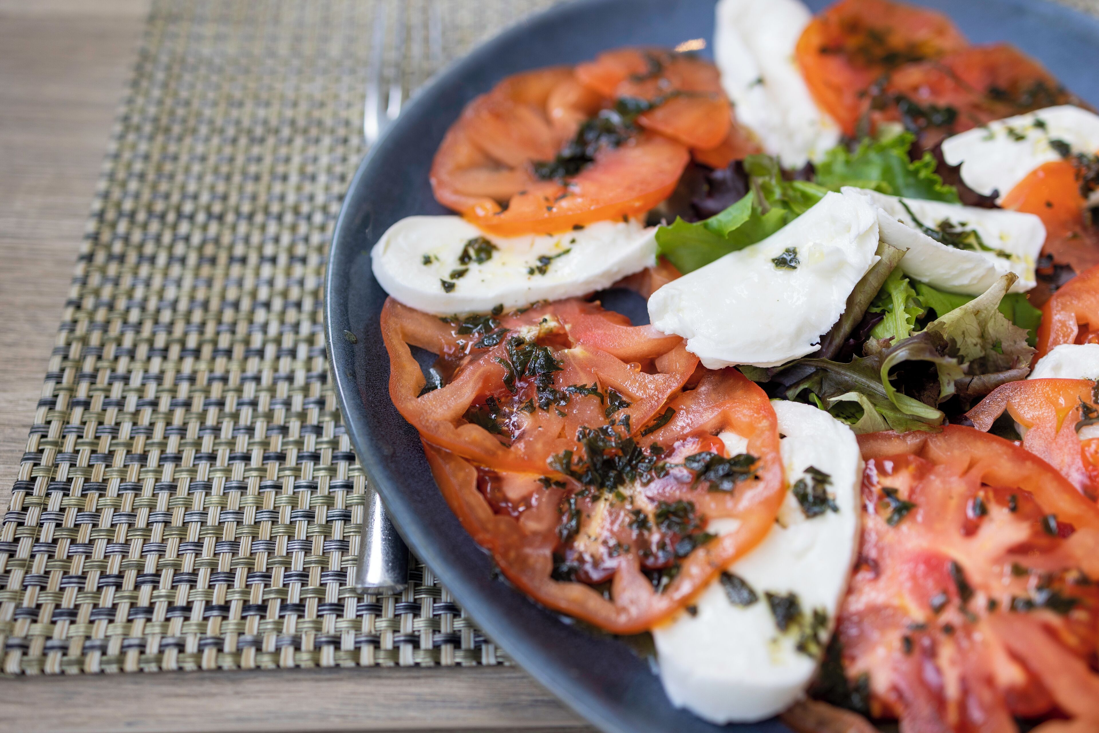 A plate of Caprese salad with tomatoes, mozzarella, and basil.