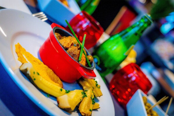 Un plato con comida, incluyendo pasta y un plato rojo con carne, y una botella verde al fondo.