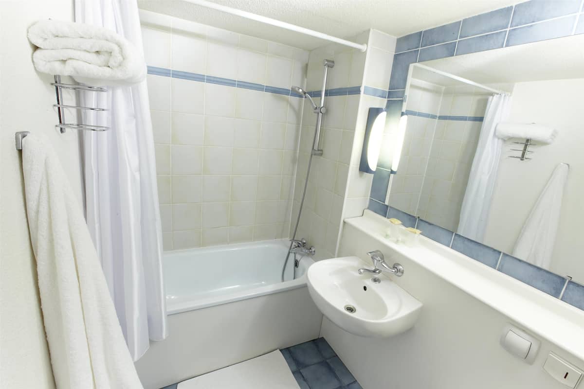 Un baño con bañera, lavamanos y espejo.