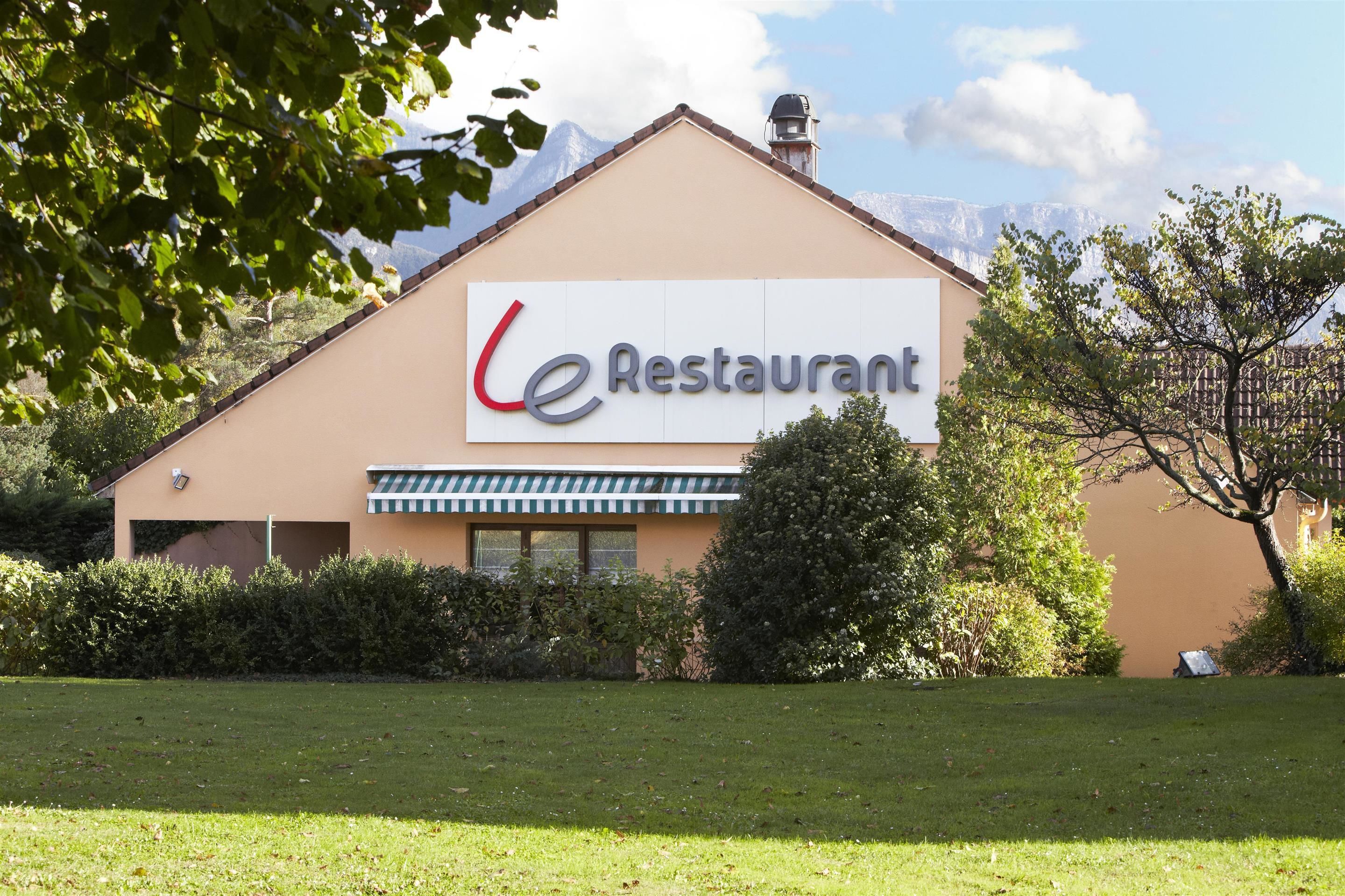 Ein Restaurantgebäude mit einem Schild, auf dem "le Restaurant" steht, vor dem Hintergrund eines Berges.