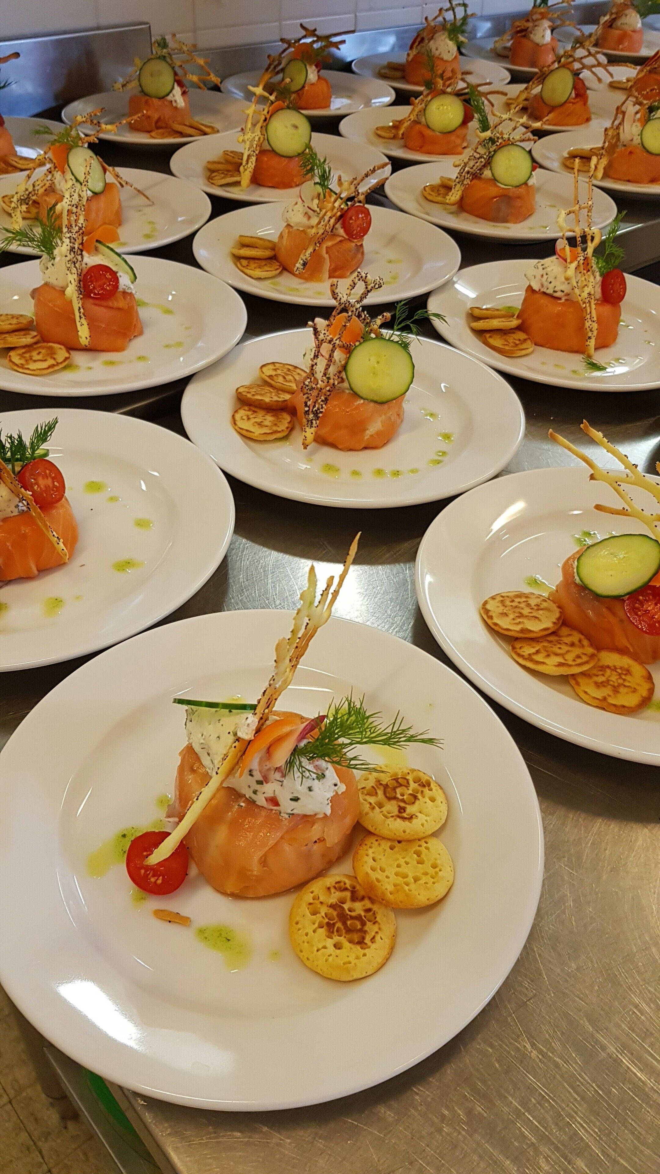 A buffet table with plates of salmon appetizers, including garnishes and sides.