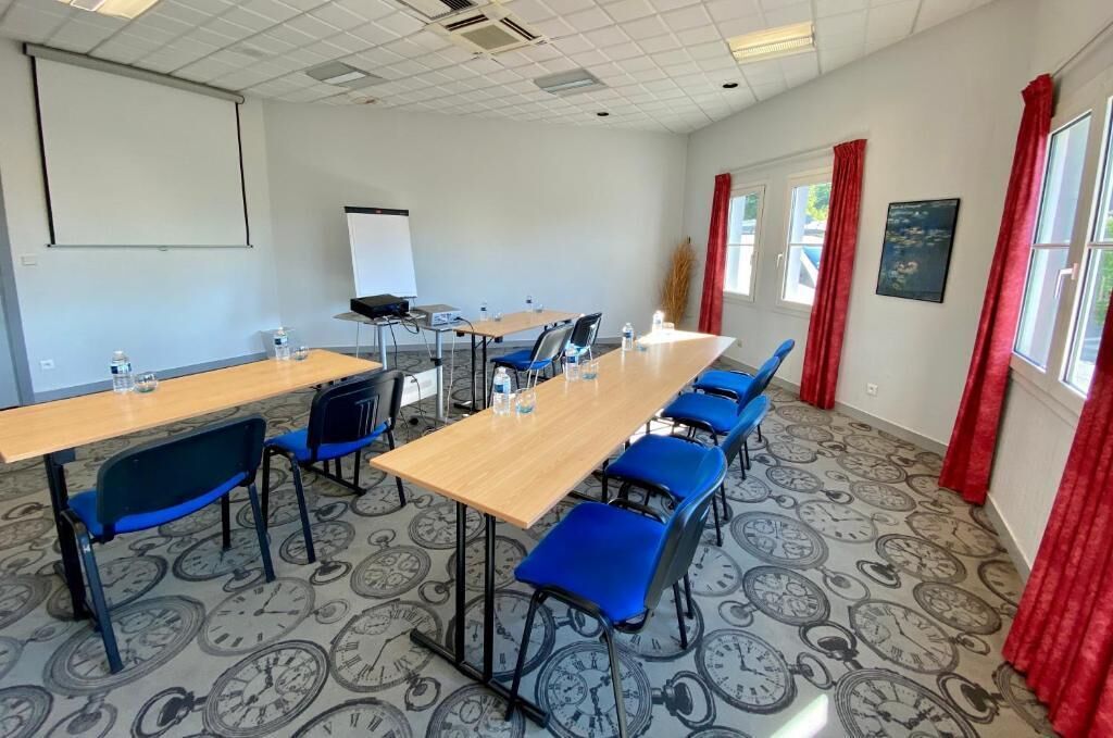 A conference room with a long table, blue chairs, a projector, and a whiteboard.