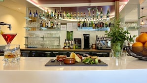 A bar area with shelves of liquor bottles, a martini glass, and a fruit bowl. - Hôtel le Néron (Fontanil-Cornillon)