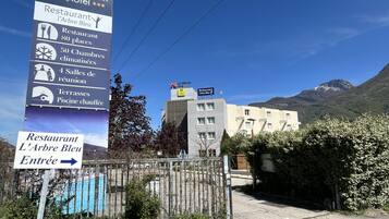 A sign for Le Neron Hotel with amenities including a restaurant, 80 places, 50 bedrooms, 4 meeting rooms, terraces, and a heated pool.