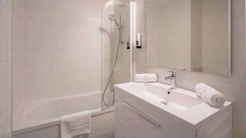 A modern bathroom with a glass-enclosed shower, a white sink with a mirror, and a towel rack.