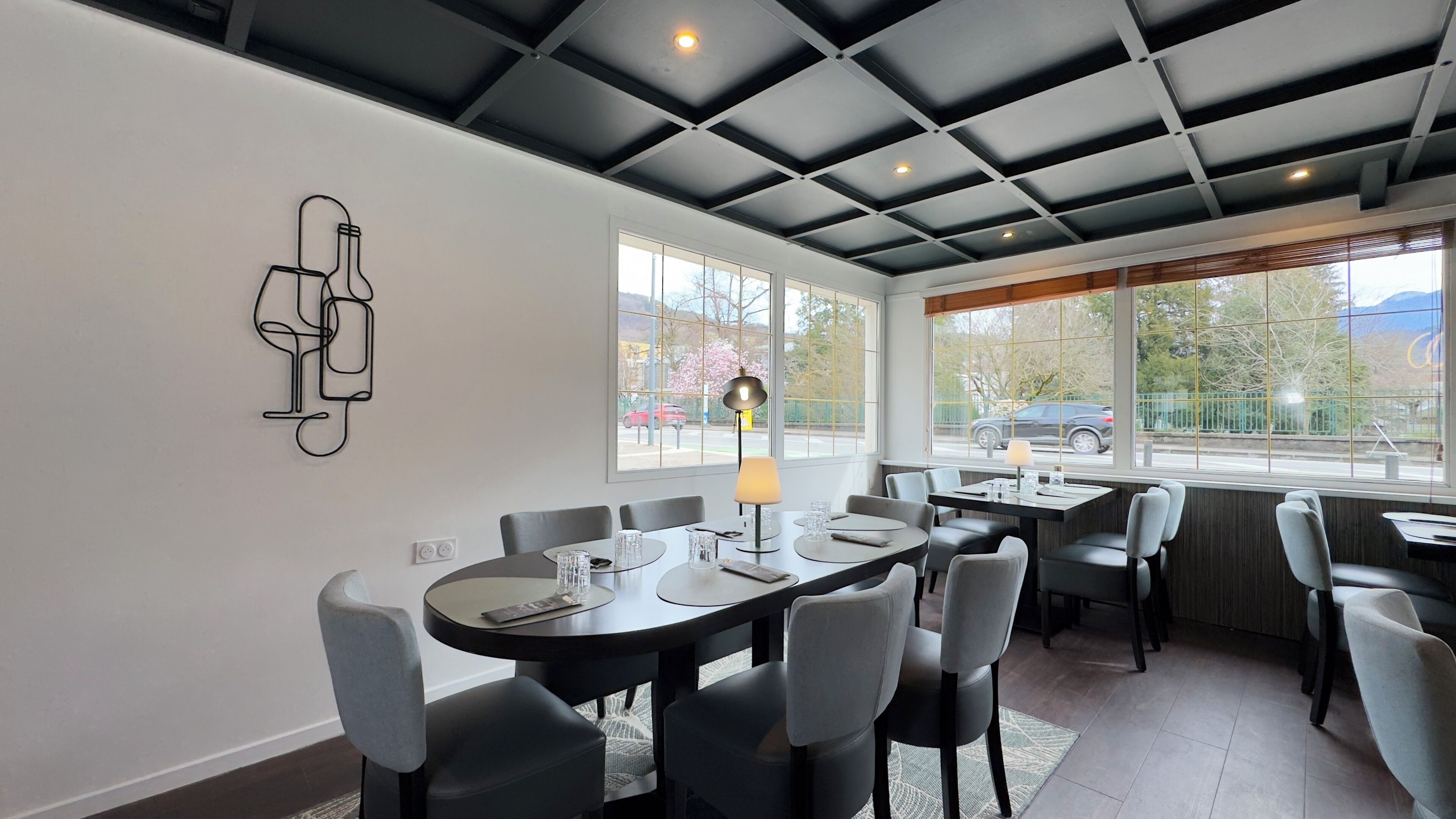 A modern dining area with a high ceiling, large windows, and a minimalist decor.