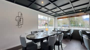 A modern dining area with a high ceiling, large windows, and a minimalist decor.