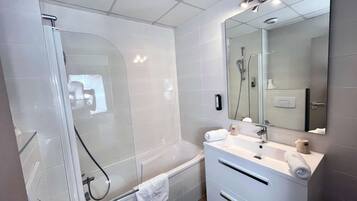 Un baño moderno con cabina de ducha de vidrio, bañera, inodoro y tocador con espejo.