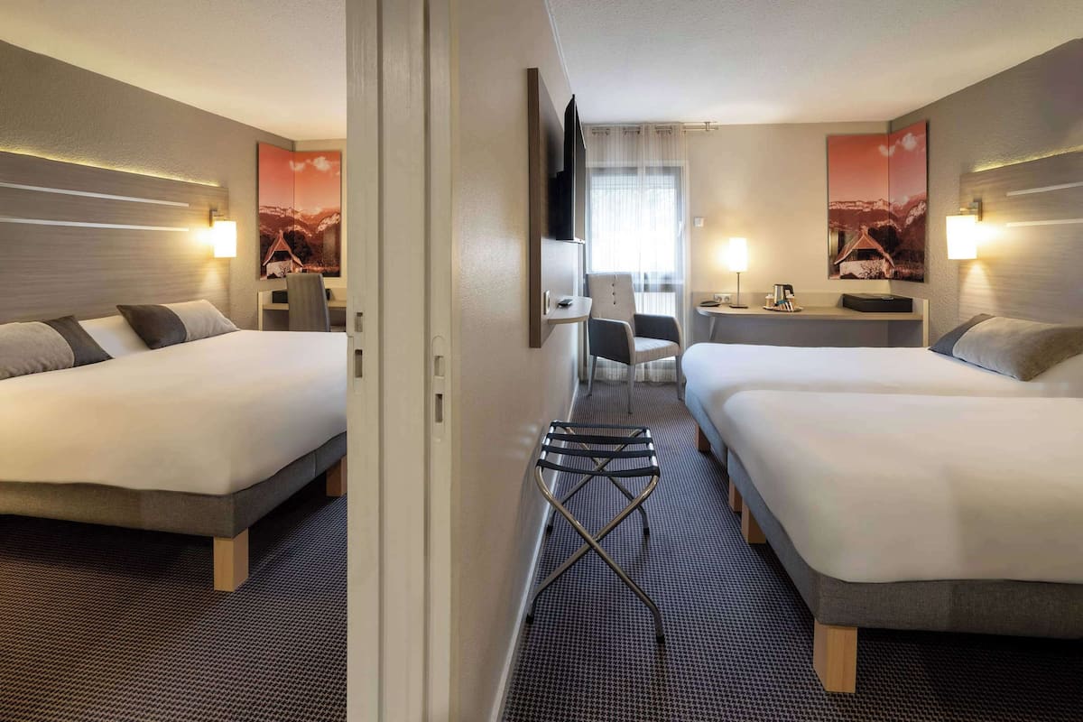 Une chambre d’hôtel avec deux lits, un bureau, une chaise et une télévision.