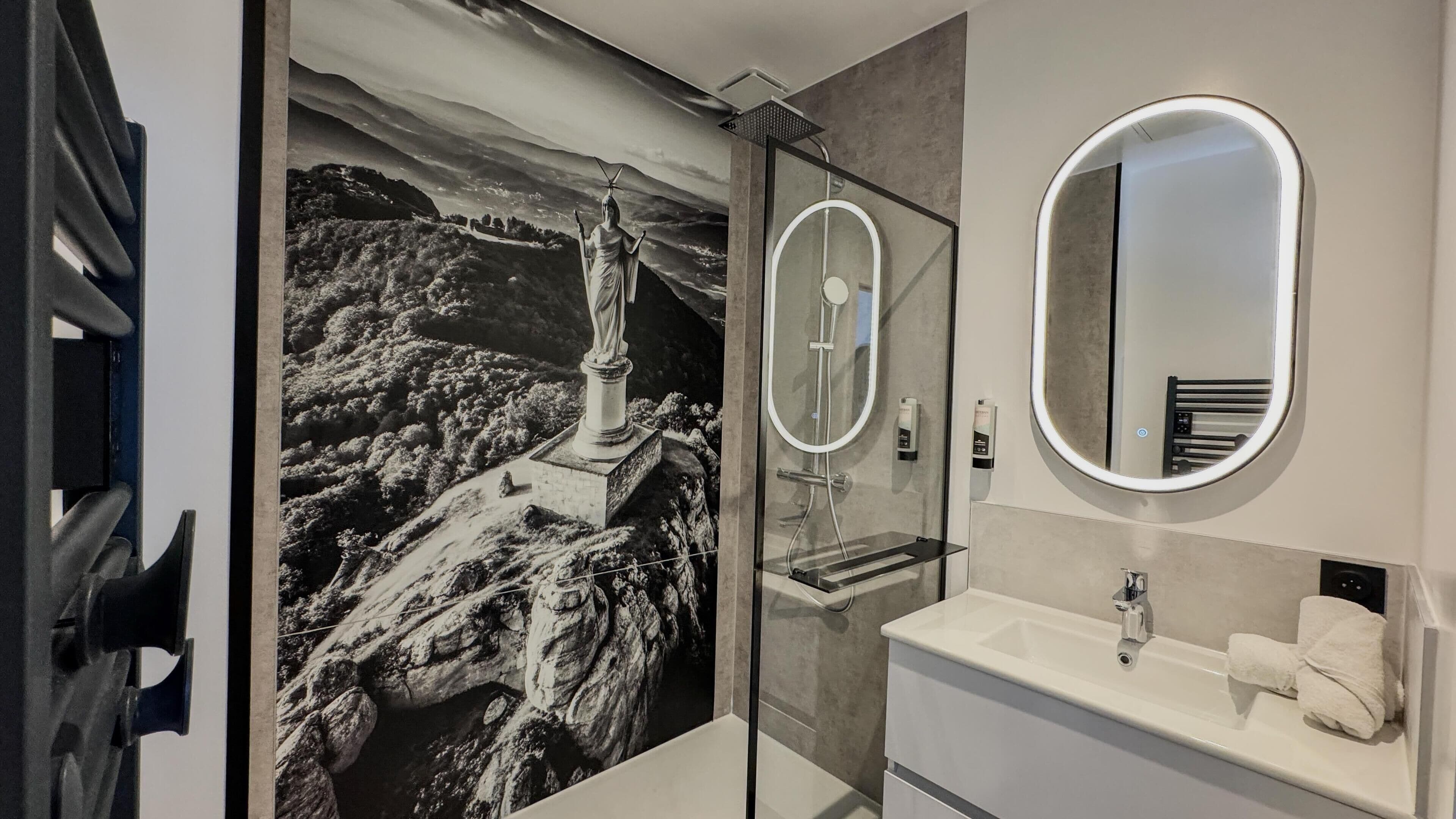 A bathroom with a large mirror, a sink, and a shower.