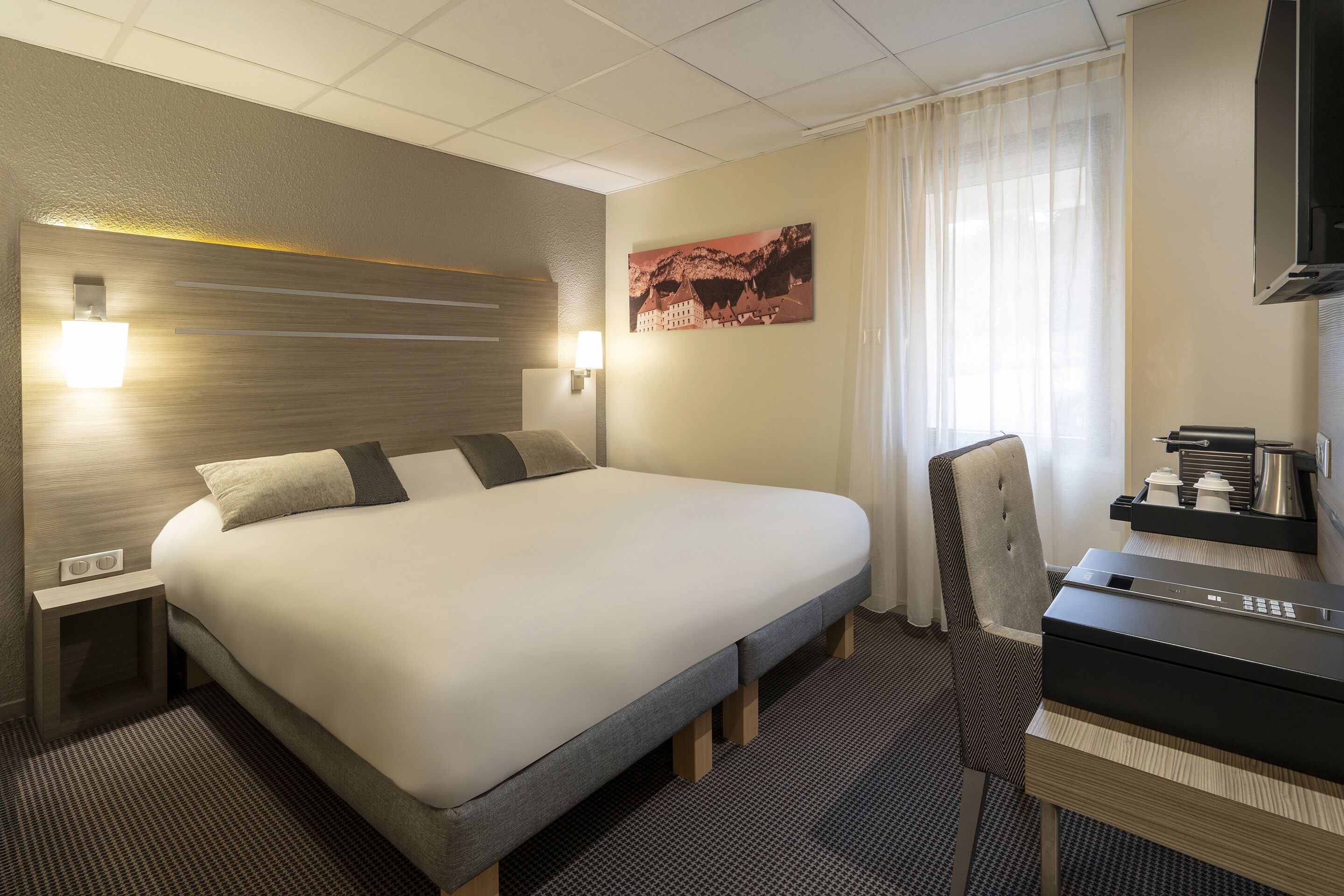 Une chambre d’hôtel avec un grand lit, des tables de chevet, un bureau et une télévision.