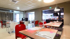 A modern restaurant with multiple dining tables and chairs, equipped with basic amenities like cutlery and glasses.