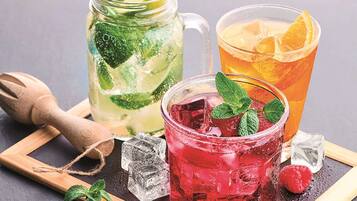 Three drinks with ice cubes, mint leaves, and citrus slices.