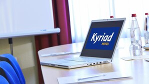 A laptop on a table displaying 'Kyriad Hotel' with a bottle of water and a glass on the table.