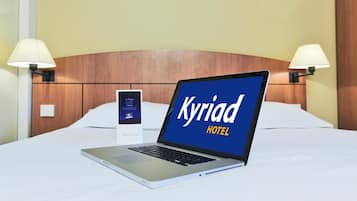 Un portatile su un letto, con sullo schermo un cartello che riporta 'Kyriad HOTEL'.