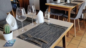 A neatly set dining table with two wine glasses, a cactus, a menu, and a small plant.