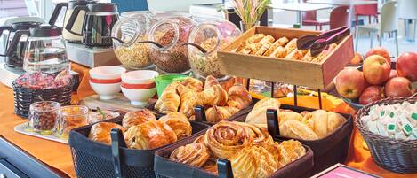 Un bufé de desayuno con diversos pasteles, frutas y bebidas.