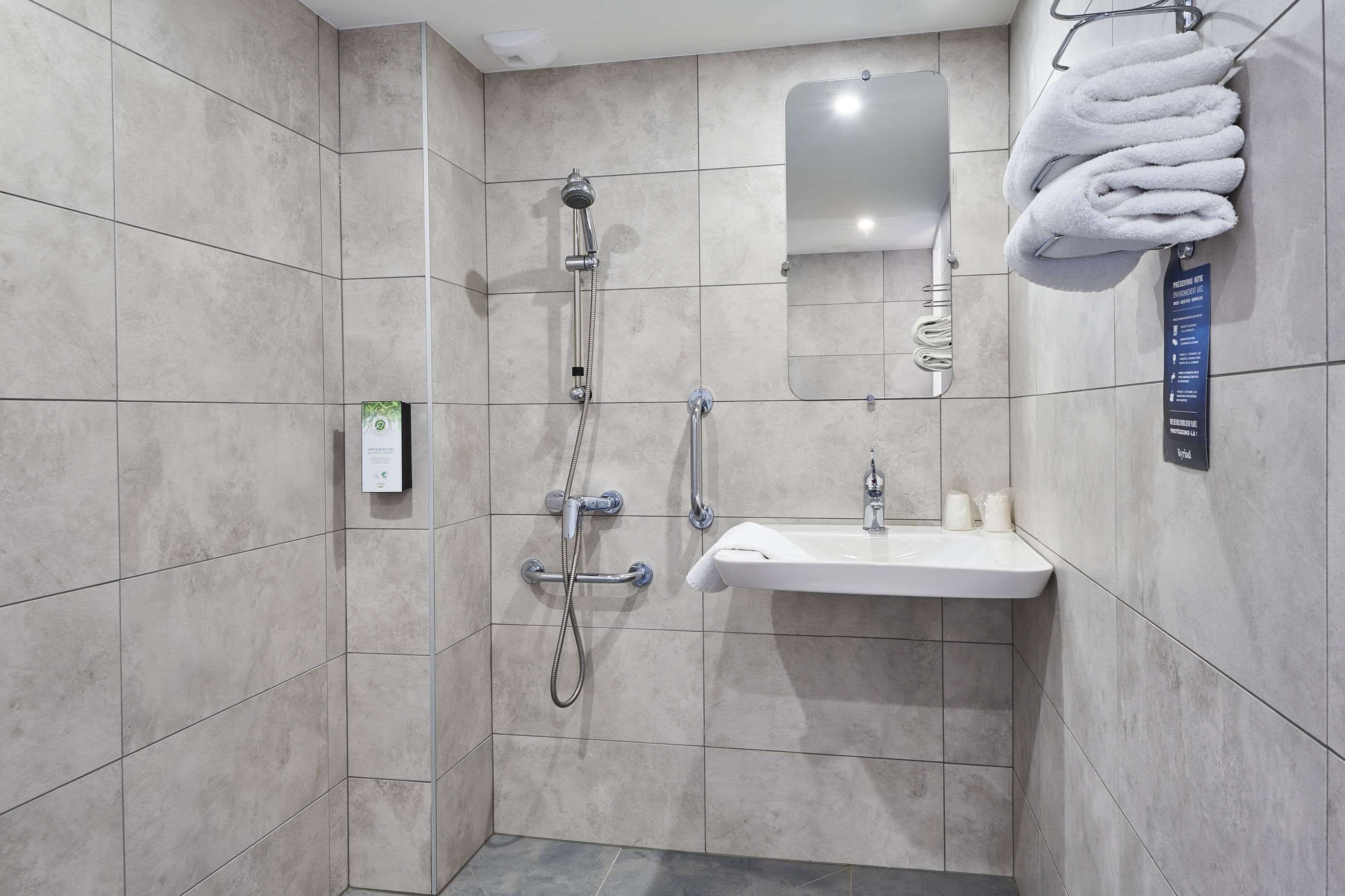 Ein modernes Badezimmer mit Dusche, Waschbecken und Handtuchhalter.