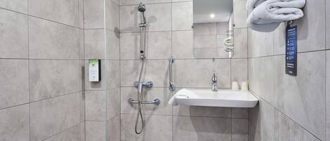 Un baño moderno con ducha, lavamanos y toallero.