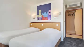 A hotel room with two beds, a wall-mounted artwork of a cityscape, a wooden headboard, a coat closet, and a carpeted floor.