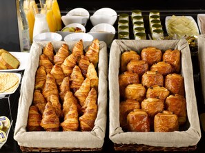 A breakfast buffet with croissants and pastries in wicker baskets.